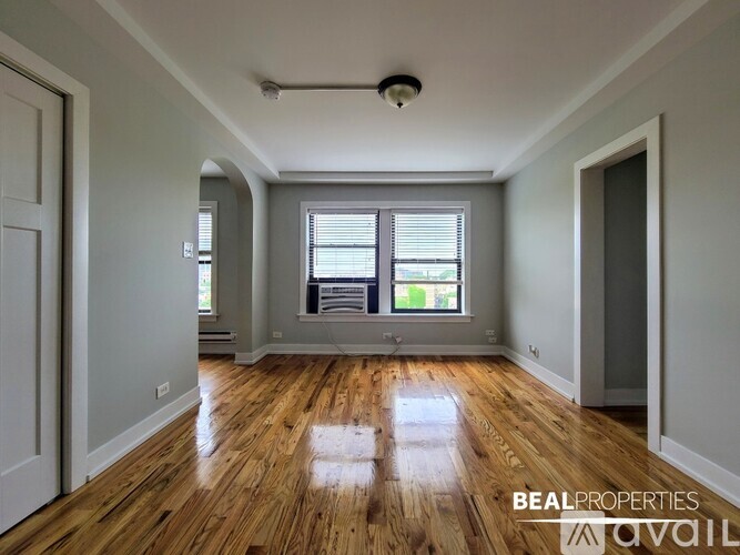 A spacious room with wooden floors and a large window.