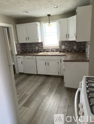 A kitchen with white cabinets and a wooden floor.