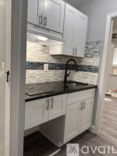 A kitchen with white cabinets and a black countertop.