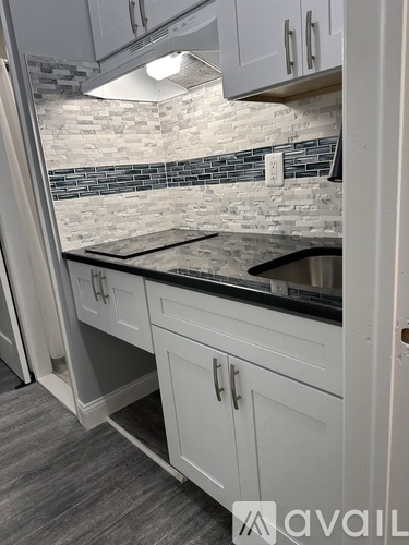 A kitchen with white cabinets and a black countertop.