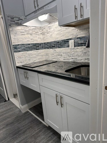 A kitchen with white cabinets and a black countertop.