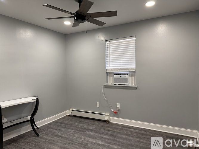 A room with a ceiling fan and a window with blinds.