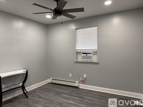 A room with a ceiling fan and a window with blinds.
