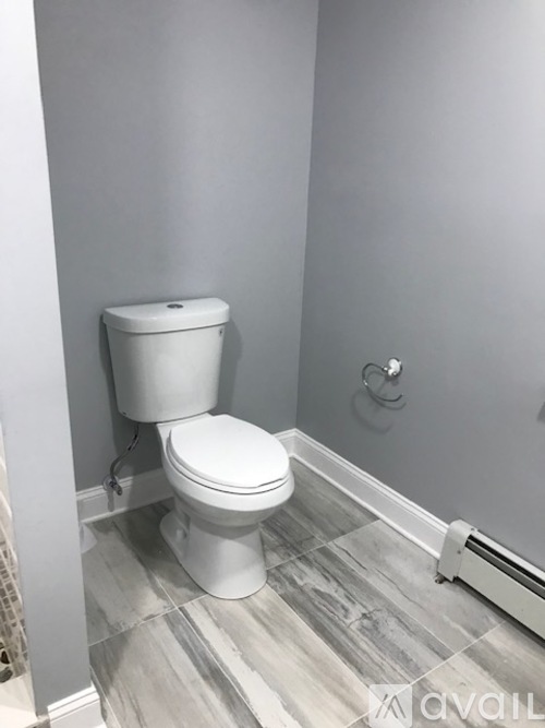 A white toilet in a bathroom with grey walls and a grey floor.