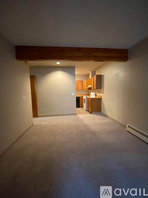 A spacious room with a wooden beam ceiling and a small kitchenette in the background.
