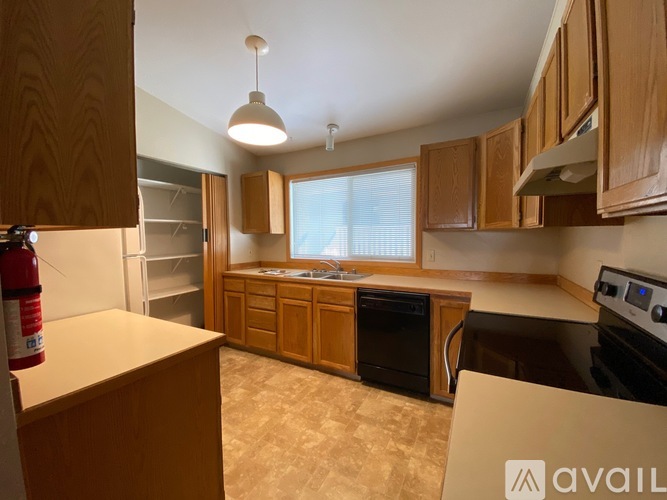 A kitchen with wooden cabinets and a black dishwasher.