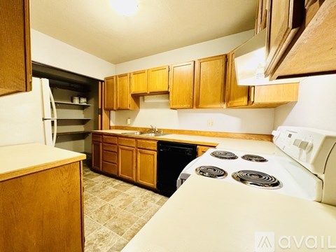 A kitchen with wooden cabinets and a black dishwasher.