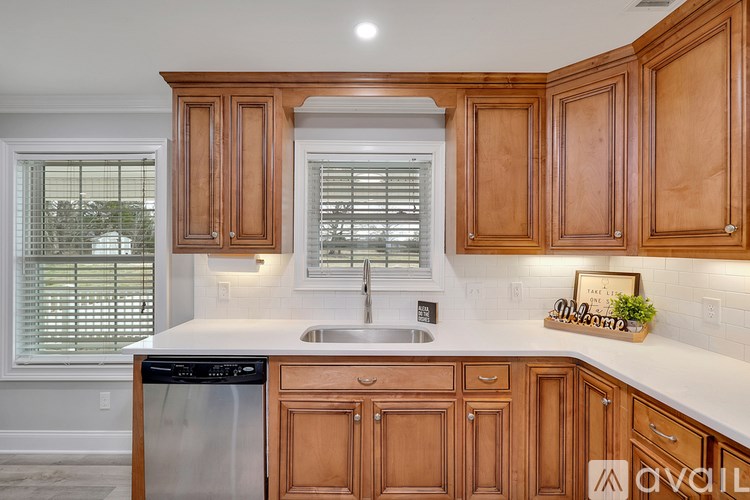 A kitchen with wooden cabinets and a stainless steel dishwasher.