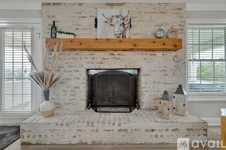A white brick fireplace with a wooden mantle and a clock on it.