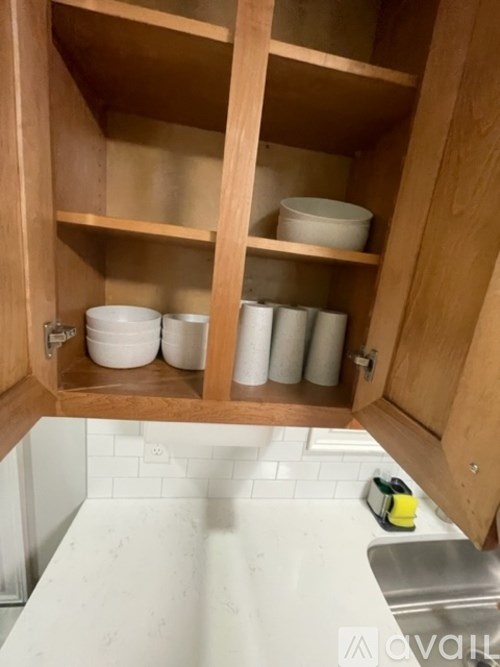 A kitchen cabinet with a bowl and cups on the shelf.