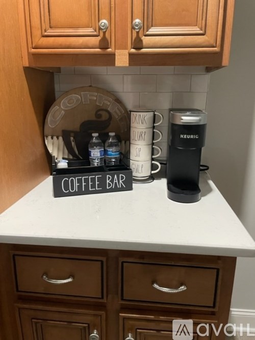 A coffee bar with a sign and a Keurig machine on a counter.