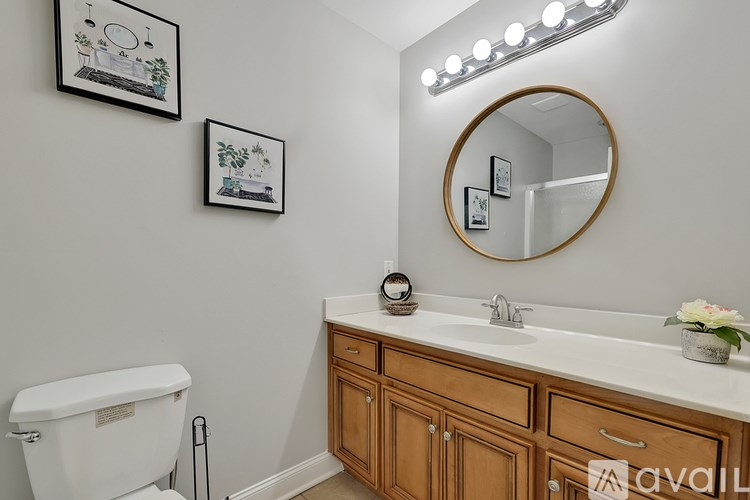 A bathroom with a toilet, sink, mirror, and lights.