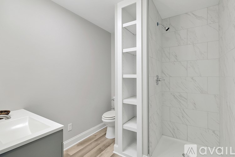 A white bathroom with a marble wall and a white toilet.