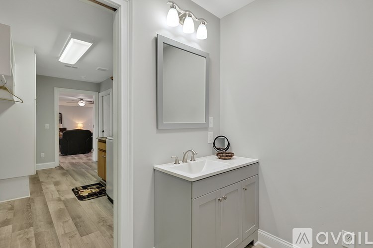 A bathroom with a sink, mirror, and light fixture.