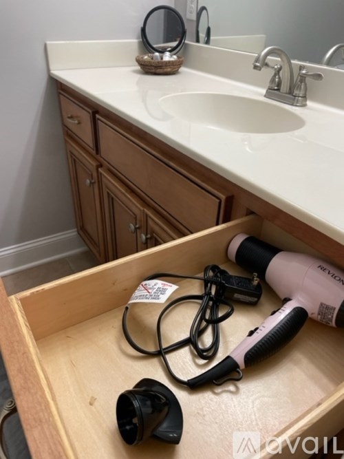 A bathroom sink with a hair dryer and a blow dryer on the counter.
