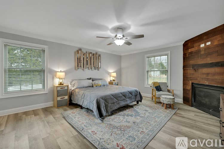 A bedroom with a bed, chair, and fireplace.