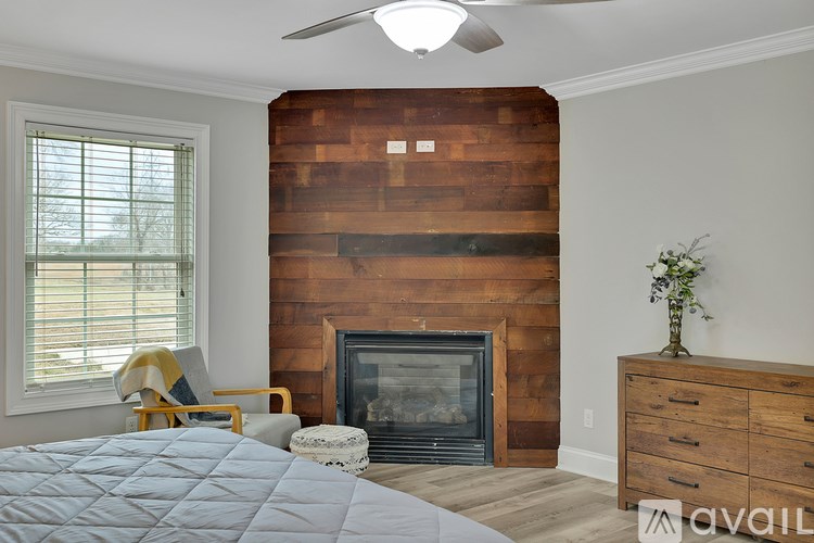 A bedroom with a large bed, a fireplace, and a wooden wall.