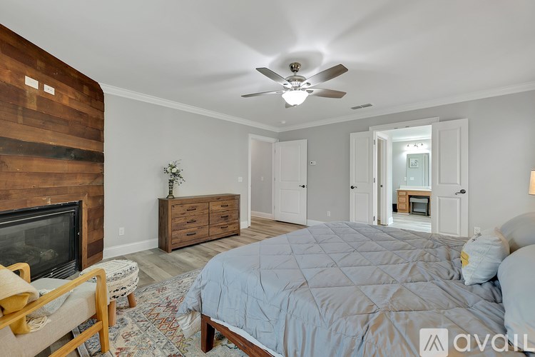 A bedroom with a bed, a fireplace, and a ceiling fan.