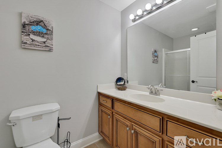 A bathroom with a white toilet, wooden cabinets, and a painting on the wall.