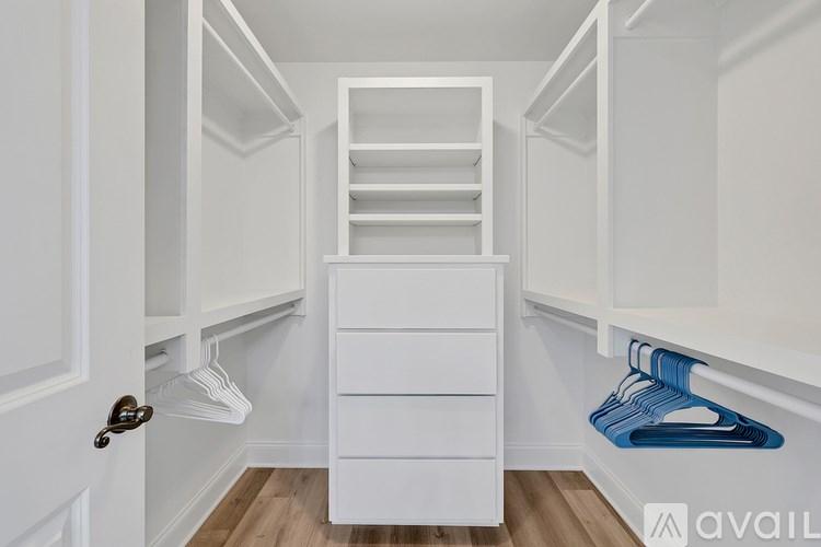 A white closet with a drawer and hangers.