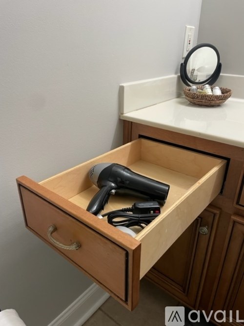 A wooden drawer with a hairdryer and a comb in it.