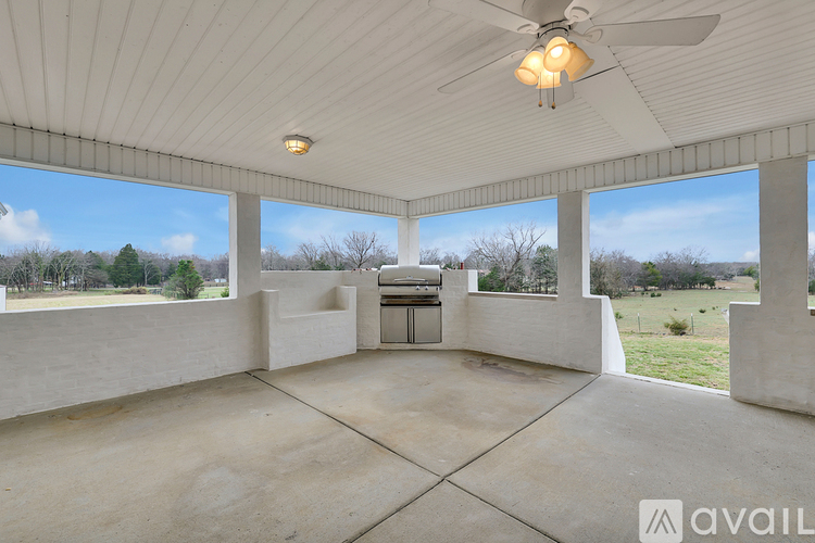 A spacious room with a ceiling fan and large windows overlooking a field.