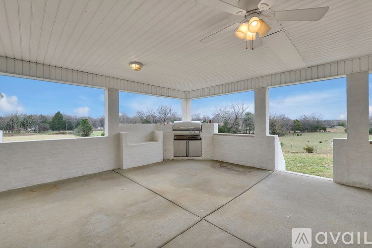 A spacious room with a ceiling fan and large windows overlooking a field.