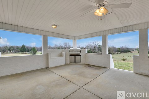 A spacious room with a ceiling fan and large windows overlooking a field.