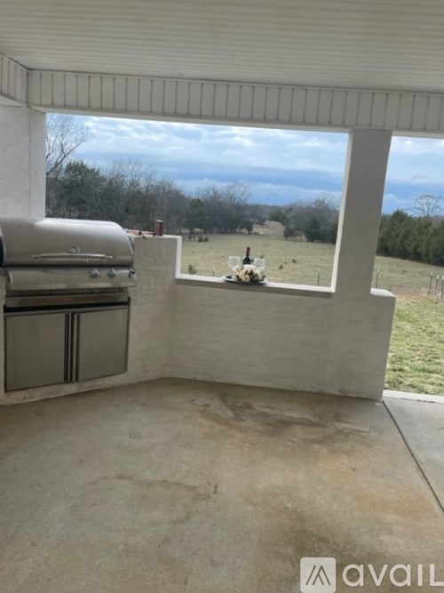 A patio with a grill and a table with a vase of flowers on it.