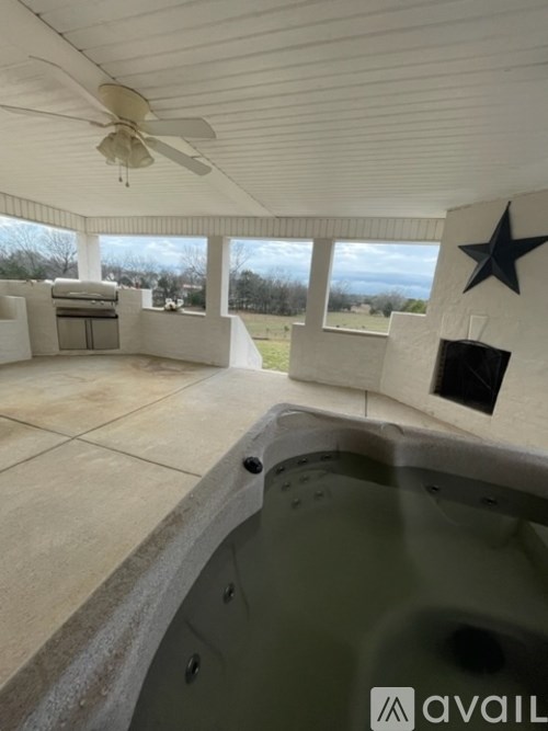 A hot tub is in the middle of a room with a ceiling fan.