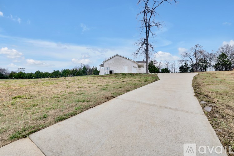 A white barn sits in a field with a concrete walkway leading to it.
