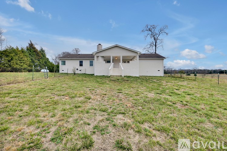 A white house with a brown roof is surrounded by a grassy field.