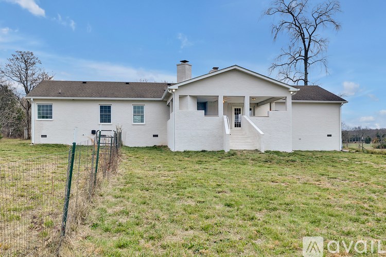 A white house with a brown roof and a fence in front of it.