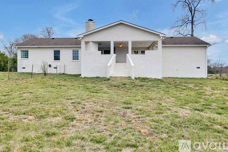 A white house with a brown roof and a tree in the background.