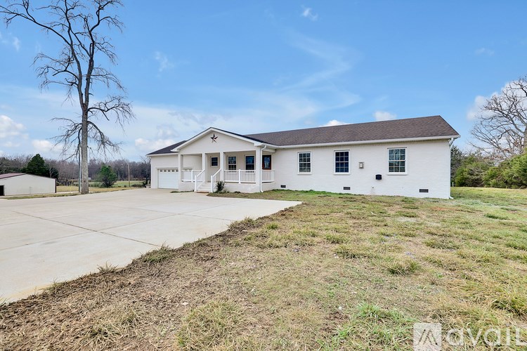 A white house with a grey roof and a driveway in front.