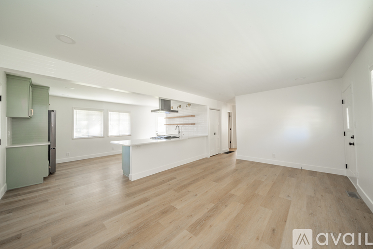 A spacious room with wooden flooring and white walls.