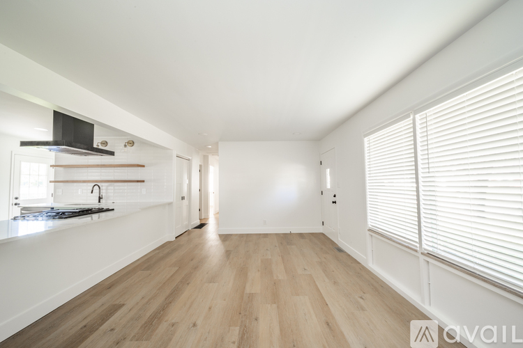 A spacious room with wooden flooring and white walls.
