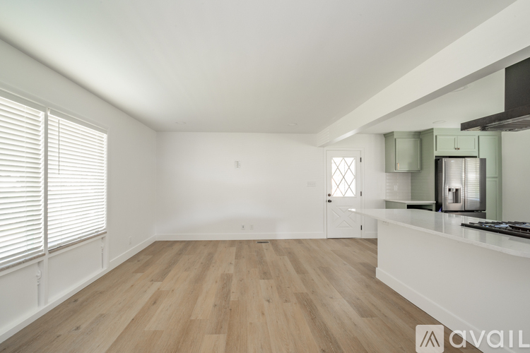 A spacious room with wooden flooring and a kitchen area with a stove and oven.