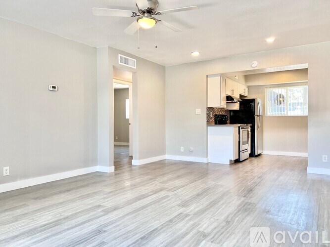 A spacious living room with a kitchen in the background.