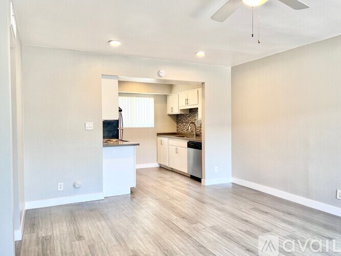 A spacious kitchen with white cabinets and a wooden floor.