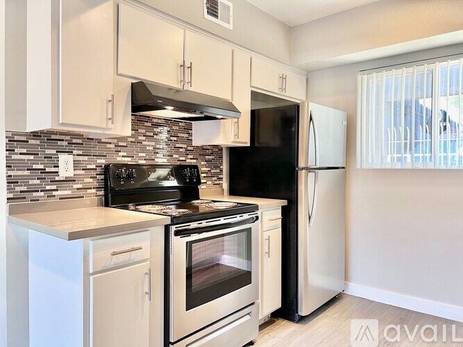 A kitchen with black and white appliances and a tiled backsplash.