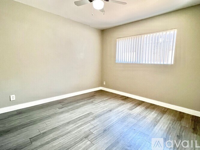 A room with a ceiling fan and a window with blinds.