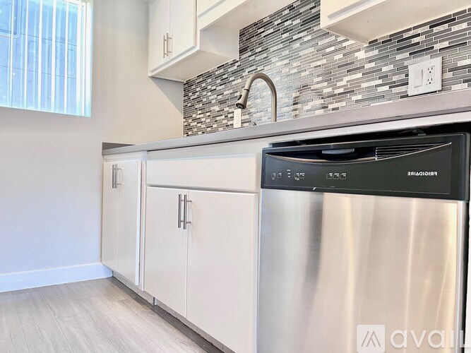 A modern kitchen with a stainless steel dishwasher and white cabinets.