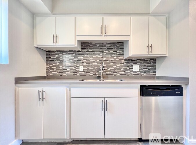 A kitchen with white cabinets and a stainless steel dishwasher.