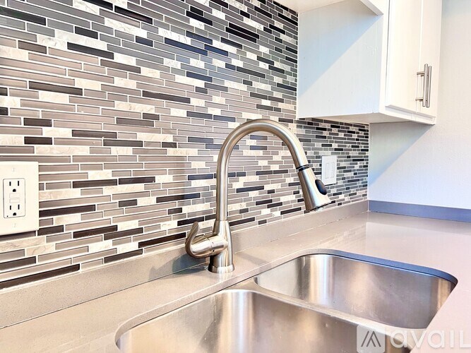 A modern kitchen with a stainless steel sink and a tile backsplash.