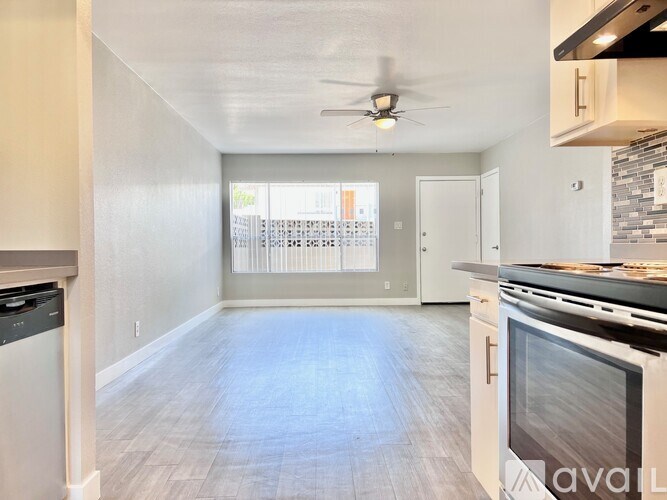 A kitchen with a stove top oven and a fan on the ceiling.