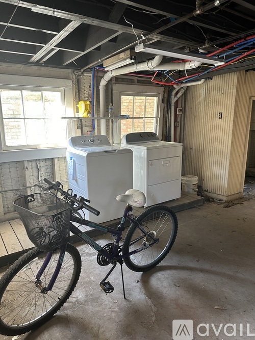 A bicycle is parked in a room with a window, a radiator, and a pipe.