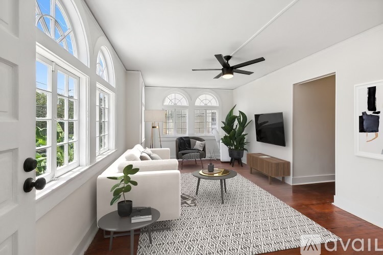 A living room with a white couch, a coffee table, and a ceiling fan.