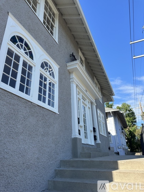 A house with a grey wall and white windows and doors.