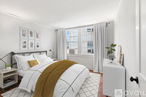 A bedroom with a large bed and a window with curtains.
